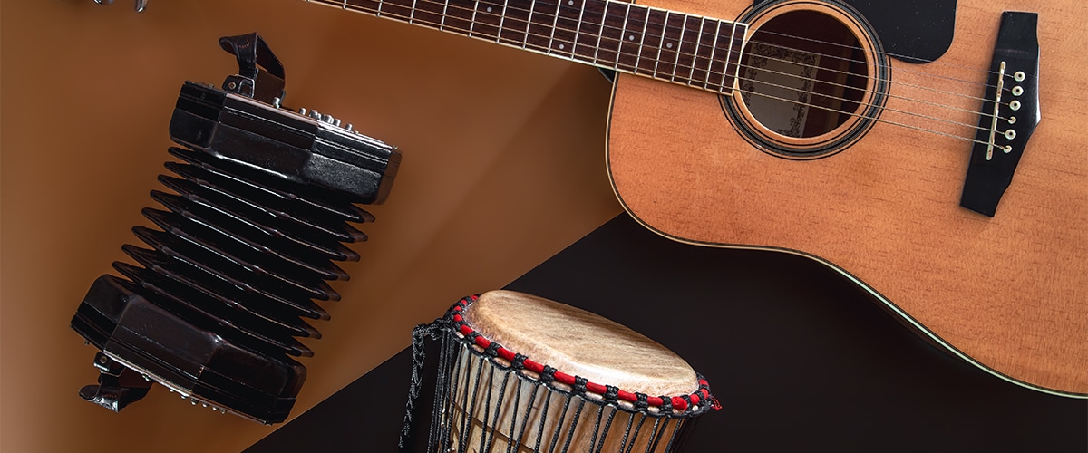 Acoustic guitar, djembe drum, and accordion displayed on a table.