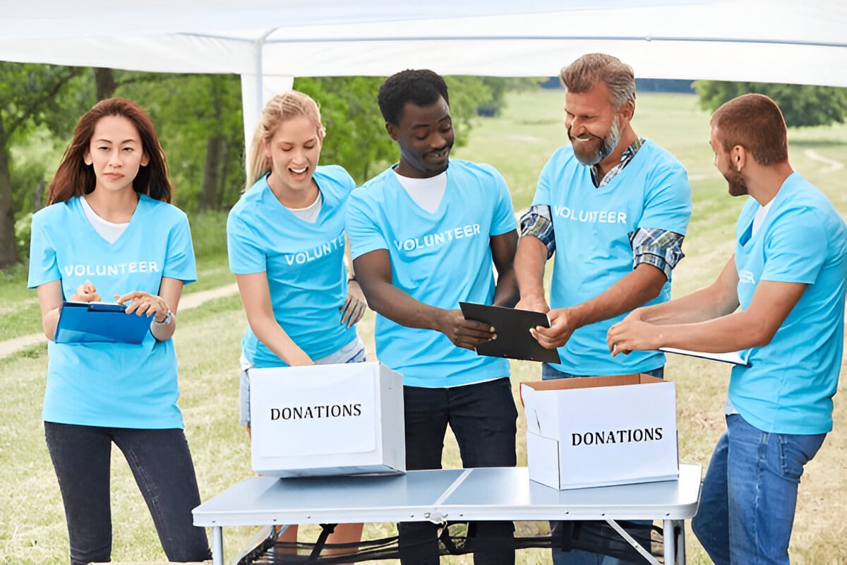 Group of volunteers wearing blue shirts sorting donations at an outdoor event.